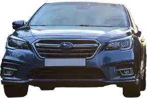A front view of a blue Subaru sedan, showing its grille, headlights, and bumper, with sunlight reflecting off the hood.