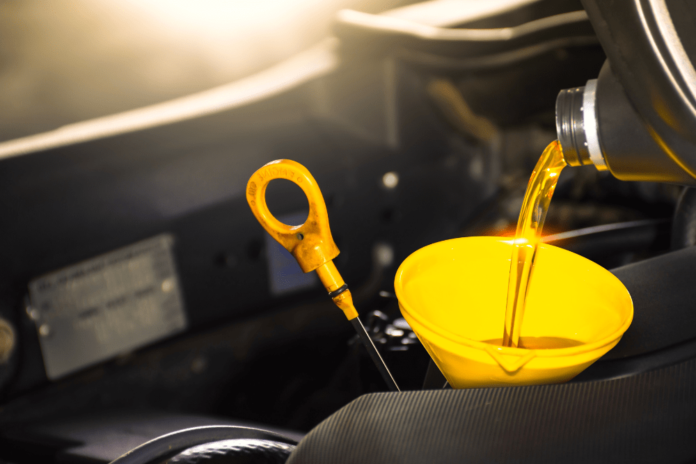 Oil change service in Newbury, MA by Angie’s Service Inc. Image showing fresh motor oil being poured into an engine with a yellow funnel, highlighting the importance of regular oil maintenance for vehicle performance and longevity.