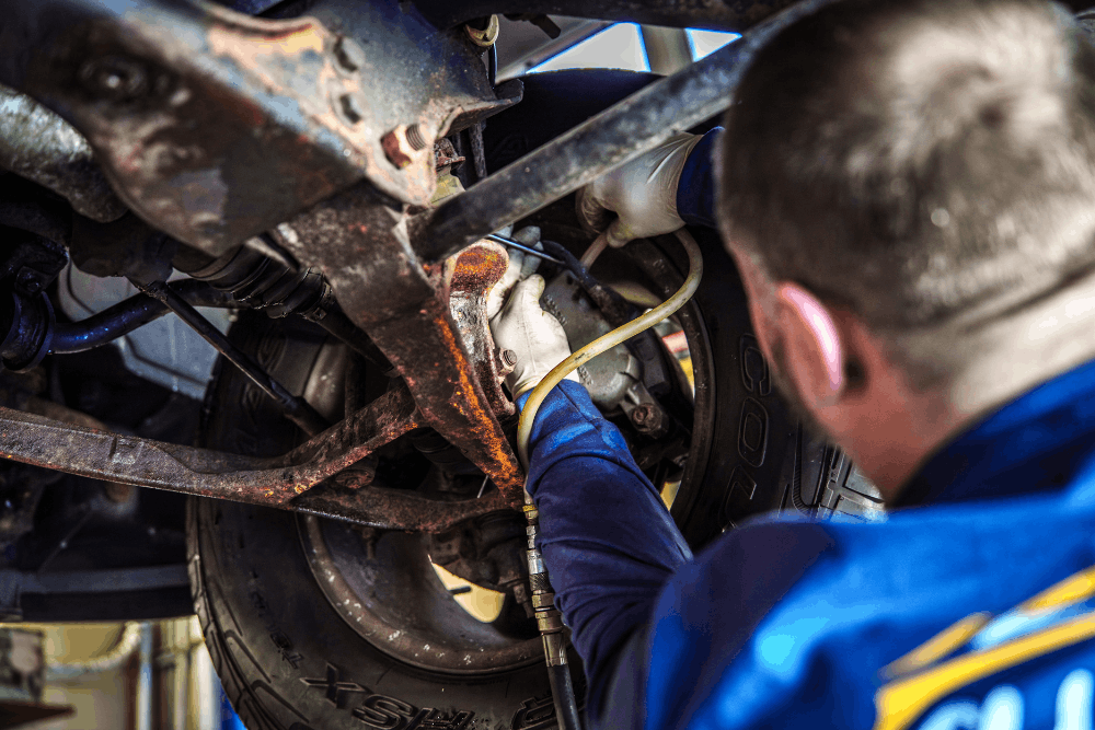 Auto repair in Newbury, MA by Angie's Service Inc. Image of a technician working underneath a vehicle, inspecting brake system components, emphasizing thorough diagnostics and dependable auto repair services for vehicle safety and performance.