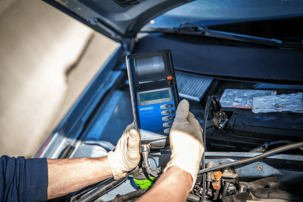 Car electrical problems, auto repair in Newbury, MA by Angie’s Service Inc. Image of technician using a digital battery tester to check vehicle battery health, ensuring reliable starts, proper charging, and dependable performance.